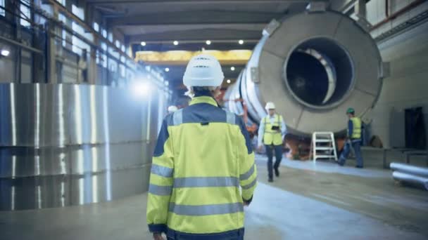 Following Shot of Heavy Industry Female Engineer Walking through Pipe Manufacturing Factory. Modern Facility for Design and Construction of Large Diameter Oil, Gas and Fuels Transport Pipeline — Stock Video