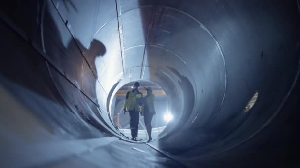 Twee ingenieurs uit de zware industrie lopen in de buis, gebruiken laptop, hebben discussie, controleren lassen. Aanleg van de olie-, aardgas- en brandstofpijpleiding Vervoer. Industriële Fabriek — Stockvideo