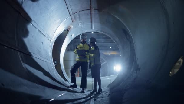 Dwóch inżynierów przemysłu ciężkiego Walking Inside Pipe, Użyj laptopa, Dyskusja, Sprawdzanie Design. Budowa rurociągu transportu ropy naftowej, gazu ziemnego i biopaliw. Fabryka Przemysłowa — Wideo stockowe