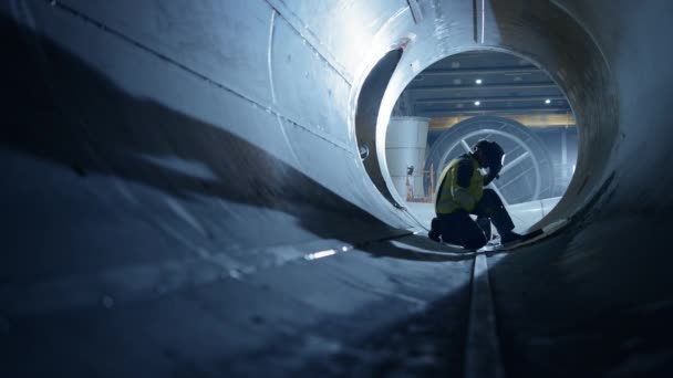 Soudeur professionnel de l'industrie lourde travaillant à l'intérieur du tuyau, porte un casque et démarre la soudure. Construction du pipeline de transport du pétrole, du gaz naturel et des combustibles. Usine de fabrication industrielle. Mouvement lent — Video