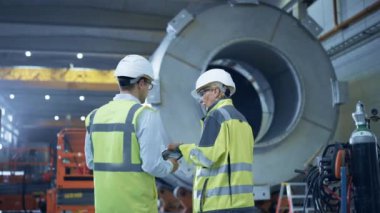 İki Ağır Sanayi Mühendisi Boru İmalat Fabrikası 'nda duruyor, Dijital Tablet Bilgisayar kullanın, Tartışıyorlar. Petrol, Gaz ve Yakıt Boru Hattı Taşıma Tesisleri