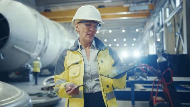 Profissional da indústria pesada engenheiro feminino vestindo uniforme de segurança, detém o computador tablet digital e explica o design do produto Olhando para a câmera. Fábrica industrial Construção de oleoduto de transporte de petróleo, gás e combustíveis — Vídeo de Stock