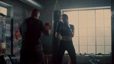 Fit Atletik Kadın Kickboxer Punches Spor Salonu'nda bir egzersiz sırasında Punching Pedleri. Çok güzel ve enerjik. Koç Boks Pedlerini tutuyor. Yoğun kendini savunma eğitimi. Mutlular ve Gülüyorlar.