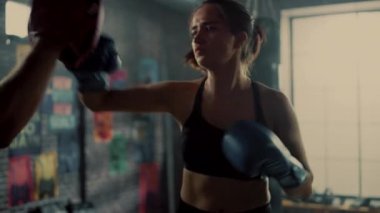 Fit Atletik Kadın Kickboxer Punches ve Bir Loft Spor Salonu'nda bir egzersiz sırasında Punching Pedleri Hits. Çok güzel ve enerjik. Güçlü Koç Boks Pedleri tutuyor. Yoğun Kendini Savunma Eğitimi.