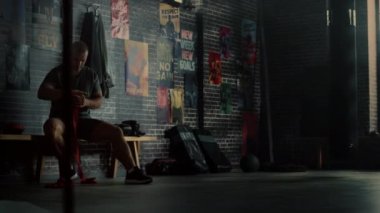 Güçlü ve Yakışıklı Erkek Hands wraps ile Duvarlarda Motivasyonposterler ile bir Spor Salonunda Onun Kickboks Egzersiz Başlatmak için Ellerini Sarma. O Bilek, Başparmak ve Eklemler etrafında Kırmızı Kayışlar kullanır.