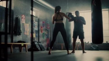 Fit Atletik Kadın Kickboxer Punches ve Bir Loft Spor Salonu'nda bir egzersiz sırasında Punching Pedleri Hits. Çok güzel ve enerjik. Güçlü Koç Boks Pedleri tutuyor. Yoğun Kendini Savunma Eğitimi.