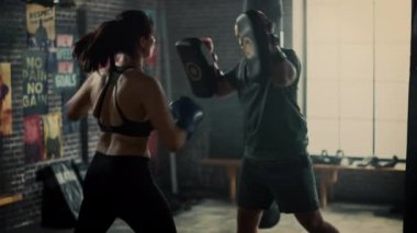 Fit Atletik Kadın Kickboxer Punches Spor Salonu'nda bir egzersiz sırasında Punching Pedleri. Çok güzel ve enerjik. Güçlü Koç Boks Pedleri tutuyor. Yoğun Kendini Savunma Eğitimi.
