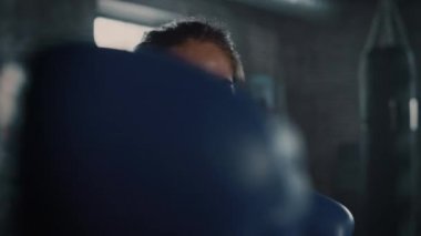 Mavi Dövüş Eldivenleri Ile Elleri Yükseltilmiş Kamera Önünde Poz Bir Güzel Fit Esmer Kickboxer Portresi. Kız Kameraya Yumruk Atıyor. Yeraltı Spor Salonu'nda..