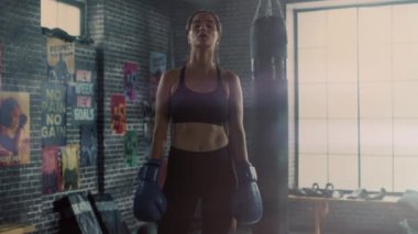 Motivasyonposterler ile Loft Gym Ayakta Güzel Fit Esmer Kickboxer Portresi. Yoğun Fitness Eğitim Programı'ndan sonra Nefesini Tutuyor. Atlet yüzünde ve vücudunda Ter var.