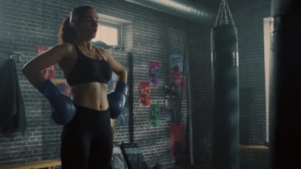 Retrato de una hermosa morena en forma Kickboxer de pie en el gimnasio Loft con carteles motivacionales. Está respirando después de un intenso programa de entrenamiento físico. Atleta tiene sudor en su cara y cuerpo . — Vídeo de stock