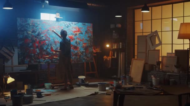 Talentvolle vrouwelijke kunstenaar die werkt aan een moderne abstracte olieverf, gebaren met brede streken met behulp van verfborstel. Dark Creative Studio Grote Picture Stands op Easel Verlicht, Gereedschap Overal — Stockvideo