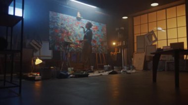 Soyut Yağlı Resimde Çalışan Yetenekli Kadın Sanatçı, Çağdaş Başyapıt Yaratan Fırça Fırçasının Geniş Vuruşları ile. Karanlık Yaratıcı Stüdyo Geniş Tuvali Easel Aydınlanmış, Araçlar Her Yerde