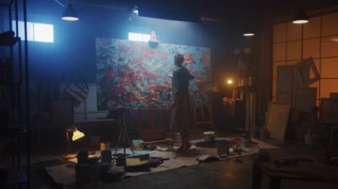 Yetenekli Kadın Sanatçı Soyut Yağlıboya Üzerine Çalışıyor, Boya Fırçası Kullanarak Modern Başyapıt ı Yaratıyor. Koyu ve Dağınık Yaratıcı Stüdyo nerede Büyük Tuval Easel Işıklı duruyor. Uzaklaştırma