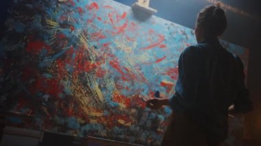 Yetenekli Kadın Sanatçı Enerjik ve Şiddetle Boya Fırçası Kullanarak O Yağlıboya Modern Masterpiece oluşturur. Çarpıcı Renkler Büyük Tuval ile Yaratıcı Stüdyo. Düşük ve Uç Açısı Atış