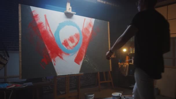 Talented Male Artist Working on an Abstract Painting, Uses Industrial Roller To Create Daringly Emotional Modern Picture. Dark Creative Studio, Large Canvas Stands on Easel. Slow Motion Zoom out — Stock Video
