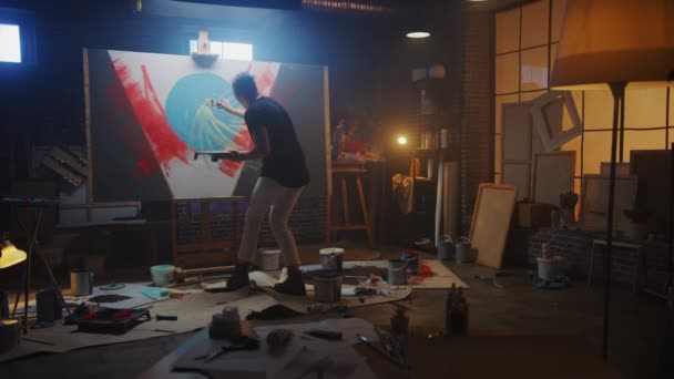 Artis Berbakat yang Bekerja pada Lukisan Abstrak, Menggunakan Tray Palette untuk Mix Colors dan Paint Brush To Create Daringly Emotional Modern Picture. Dark Creative Studio, Large Canvas Stands on Easel Illuminated — Stok Video