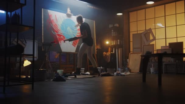 Talentvolle kunstenaar die werkt aan Abstract Painting, maakt gebruik van Tray Palette om kleuren en penseel te mengen om Daringly Emotional Modern Picture te creëren. Dark Creative Studio Grote Canvas Stands op Easel Verlicht — Stockvideo