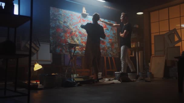 Dans la classe d'art : une jeune artiste talentueuse peint avec un pinceau sur la grande toile, son éminent peintre mentor lui enseigne la technique et les styles — Video