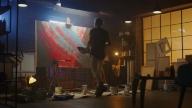 Yetenekli Erkek Sanatçı Soyut Bir Resim Üzerinde Çalışıyor, Cesurca Duygusal Modern Resim Oluşturmak için Endüstriyel Roller kullanır. Dark Creative Studio Büyük Tuval Easel Işıklı Standları
