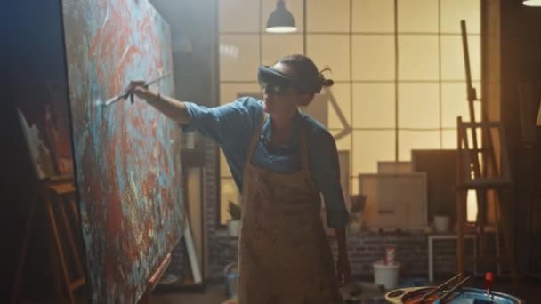 Getalenteerde vrouwelijke artiest met augmented reality headset werken aan abstract schilderen, gebruikt Paint Brush om nieuwe concept kunst te creëren met behulp van Virtual Reality interface. Hightech creatieve moderne studio — Stockvideo