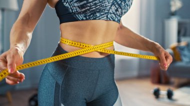 Minimalist İç Meslek ile Onun Parlak ve Ferah Oturma Odasında Bir Bant Cetvel ile Onu Bel Ölçme Atletik Bir Üst Güçlü ve Güzel Busty Fit Kız Close Up.