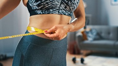 Minimalist İç Meslek ile Onun Parlak ve Ferah Oturma Odasında Bir Bant Cetvel ile Onu Bel Ölçme Atletik Bir Üst Güçlü ve Güzel Busty Fit Kız Close Up.