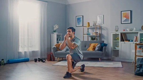 Strong Athletic Fit Man w T-shirt i szorty robi naprzód Lunge ćwiczenia w domu w jego przestronne i jasne mieszkanie z minimalistycznym wnętrzem. — Zdjęcie stockowe