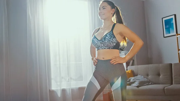 Bliska silnej i pewny siebie Athletic fitness dziewczyna w Sportswear robi naprzód Lunge ćwiczenia w jej słoneczny i przestronny pokój dzienny z nowoczesnym wnętrzem. — Zdjęcie stockowe