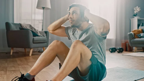 Strong Athletic Fit Man in T-shirt and Shorts is Doing Abdominal Crunch Workout at Home in His Spacious and Bright Living Room with Minimalist Interior. — Φωτογραφία Αρχείου
