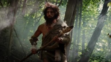 Tarih öncesi ormanda Hayvan Derisi Giyen İlkel Mağara Adamı 'nın Portresi ve Taş Ucu Mızrakla Kürk Avı. Tarih öncesi Neandertal Avcısı Ormanda İlkel Aletlerle Çöpleri Arıyor