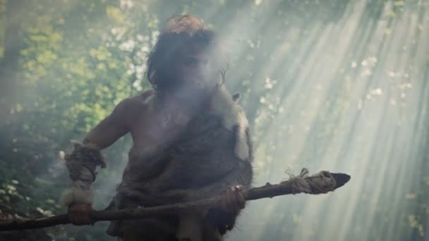 Retrato de Caveman Primeval vestindo pele de animal e caça à pele com uma lança de pedra na floresta pré-histórica. Caçador Neandertal Pré-histórico Caçando com Ferramentas Primitivas na Selva — Vídeo de Stock