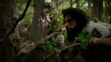 Tarih öncesi ormanda Hayvan Derisi Giyen İlkel Mağara Adamı 'nın Portresi ve Taş Ucu Mızrakla Kürk Avı. Tarih öncesi mağara adamı Avcısı Ormana Mızrak Atmaya Hazır