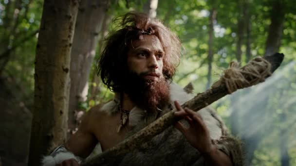 Portrét pravěkého jeskynního muže s kůží zvířete a lovem kožešin s kopím s hrotem z kamene v pravěkém lese. Prehistorický neandrtálský lovec připraven hodit kopí do džungle — Stock video