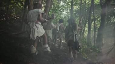 Hayvan Derisi Tutan Taş Uçlu Araçlar Giyen Avcı-Toplayıcılar Kabilesi, Hayvan Avı'nda Tarih Öncesi Ormanı Keşfedin. Ormanda Neandertal Aile Avcılık veya Göç. Aşağıdaki Görünüm