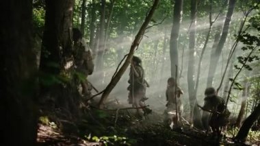 Hayvan Derisi Tutan Taş Uçlu Araçlar Giyen Avcı-Toplayıcılar Kabilesi, Hayvan Avı'nda Tarih Öncesi Ormanı Keşfedin. Ormanda Neandertal Aile Avcılık veya Göç. Yan Görünüm