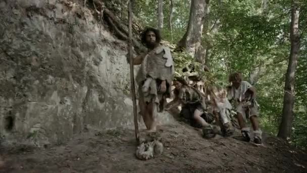 Tribe of Hunter-Gatherers Wearing Animal Skin Living in a Cave. Preparando comida, construyendo hogueras, manejando cueros, trabajando, cazando. Feliz familia neandertal en el amanecer de la civilización humana — Vídeo de stock