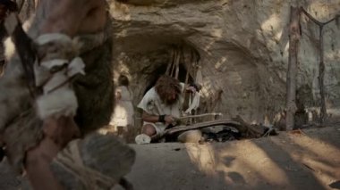 Primeval Caveman Bow Matkap Yöntemi ile Yangın yapmaya çalışıyor Hayvan Deri Giyen. İnsan Uygarlığı Tarihinde Neandertal Kindle İlk İnsan Yapımı Ateş. Yemek Pişirmek için Ateş Yapmak. Çekimi Yakınlaştır
