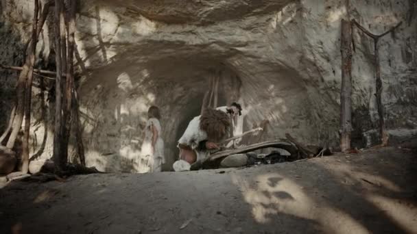 動物の皮膚を身に着けている原始の洞窟人は、弓ドリル法で火を作ろうとしています。ネアンデルタール・キンドル人類文明史上初の人工火災料理のための火を作る。ズームインショット — ストック動画