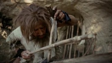 Primeval Caveman Bow Matkap Yöntemi ile Yangın yapmaya çalışıyor Hayvan Deri Giyen. İnsan Uygarlığı Tarihinde Neandertal Kindle İlk İnsan Yapımı Ateş. Yemek Pişirmek için Ateş Yapmak. Yavaş Çekim