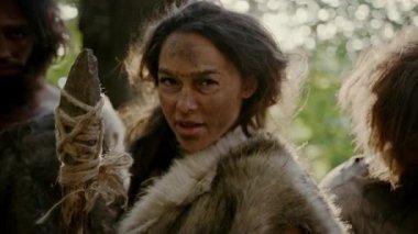 Kadın Lider ve Hayvan Derileri Giyen İki Primeval Cavemen Saldırı Düşman Taş Uçlu Mızrak, Scream, Prehistorik Times Onların Mağara ve Toprakları Savunan. Neandertaller / Homo Sapiens Kabilesi