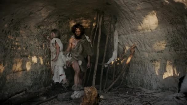 Tribe of Hunter-Gatherers Wearing Animal Skin Live in a Cave (en inglés). Líder sostiene piedra punta herramienta, ir a la caza de presas de animales, Cocina hembra comida en hoguera, Chica dibujando en Wals, Creación de primer arte. Familia Neandertal o Homo Sapiens — Vídeo de stock