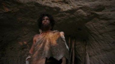 Hayvan Derisi Giyen Primeval Caveman Portresi Mağara Bırakır ve Bir Taş Uçlu Mızrak ile Avcılık Goes. İlkel Neandertal Avcısı / Homo Sapiens Güneşte Şaşılar Den'den Çıkıyor.