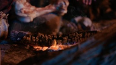 Tarih öncesi avcı-toplayıcı kabilesi Hayvan Derisi Giyen Gece Bir Mağarada Yaşıyor. Neanderthal ya da Homo Sapiens Ailesi Şenlik Ateşi 'nde Isınmaya Çalışıyor, Ateşin Üzerinde Elele tutuşuyor, Yemek Pişiriyor