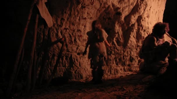 Primitive Prehistoric Neanderthal Child Wearing Animal Skin Draws Animals and Abstracts on the Walls at Night. Creating First Cave Art with Petroglyphs, Rock Paintings. Back View Following Shot — Stock Video