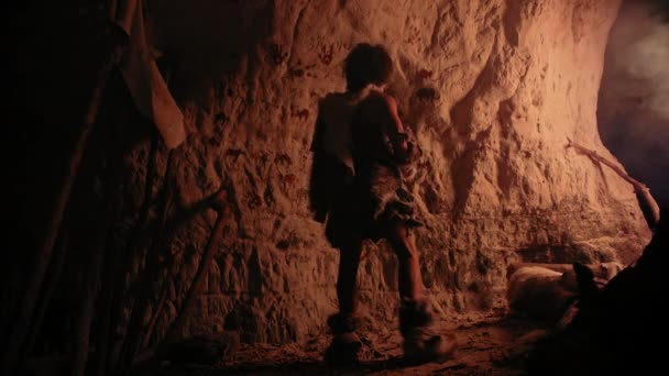 Primitive prähistorische Neandertaler, die Tierhaut tragen, malen nachts Tiere und Abstraktionen an die Wände. Erste Höhlenkunst mit Felszeichnungen, Felsmalereien, die vom Feuer erleuchtet werden. Zurück zur Ansicht — Stockvideo