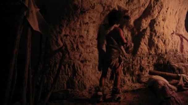 Pré-histórico primitivo Neandertal vestindo pele de animal desenha animais e resumos nas paredes à noite. Criando Primeira Caverna Arte com Petroglifos, Pinturas Rochosas Iluminadas pelo Fogo. Voltar Ver Zoom em — Vídeo de Stock