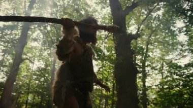 Hayvan Derisi Giyen Primeval Caveman Tutar Taş Mızrak Prehistorik Orman Etrafında Görünüyor, Hayvan Av Hunt hazır. Taş Devri Neandertal Ormana Avcılık Gidiyor. Düşük Açılı Yavaş Hareket Ark Çekimi