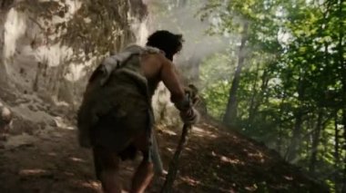 Hayvan Derisi Giyen Primeval Caveman Tutar Taş Uçlu Çekiç Etrafına Bakar, Prehistorik Ormanı Keşfetmek, Hayvan Avı'na Hazır. Neandertal Ormana Avlanmaya Gidiyor. Geri Görünüm Çekimini Takip Edin