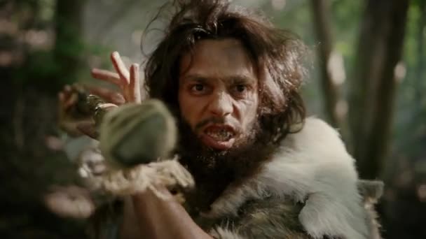 Retrato de Caveman Primeval vestindo pele de animal e caça à pele com uma lança de pedra na floresta pré-histórica. Neandertal pré-histórico gritando, ameaçando e atacando — Vídeo de Stock