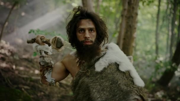 Porträtt av den primitiva grottmannen med djurhud och pälsjakt med ett stenspetsat spjut i den förhistoriska skogen. Förhistorisk neandertalare Skrik, hota och attackera — Stockvideo